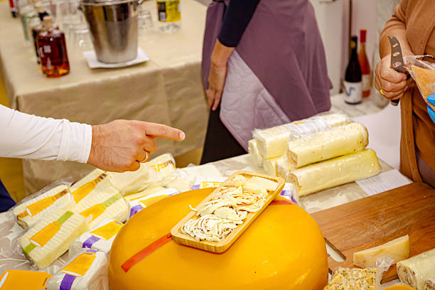 Woman is selling various type of homemade cheese at indoor stall, stand, private event.