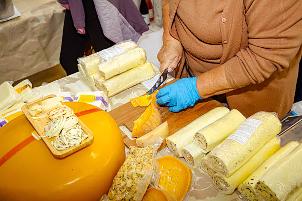 Woman is selling various type of homemade cheese at indoor stall, stand, private event.