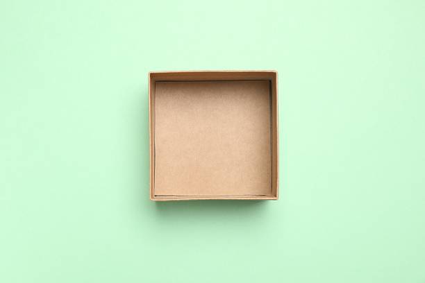 Caucasian female holding cardboard box with blank label in casual setting.