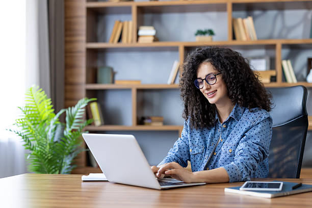 istock Smiling woman working on laptop in home office 2253464151
