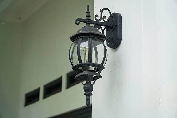 Mounted on a white exterior wall, this classic black outdoor wall lamp features a clear glass globe housing a modern LED bulb, providing exterior illumination