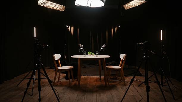 istock Two Microphones Stand Ready on a Wooden Table, Surrounded by Soft Lighting in a Modern Studio 2253466285