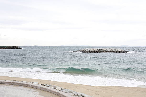 A cloudy winter sky and a rough Seto Inland Sea beach scene in Iyo City, Ehime Prefecture.