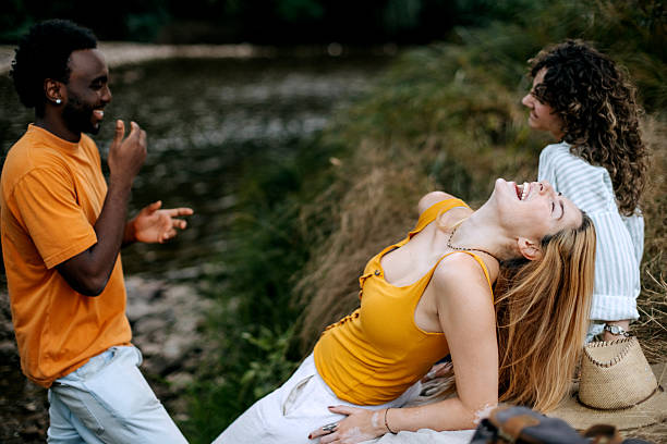 A group of young friends relaxes and enjoys time together by the river. Captures friendship, outdoor leisure, and a calm natural atmosphere.