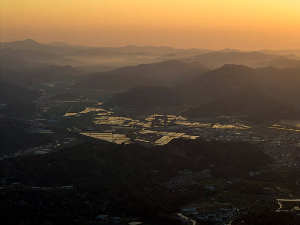Captivating aerial view of a sunset casting warm hues over a mountain range, with misty valleys below. The scene is tranquil and picturesque, ideal for nature photography or travel promotions.
