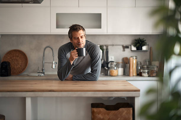 istock Relaxed Man Sips Coffee In Modern Kitchen At Wooden Island Counter, Morning Routine Setting 2253469202