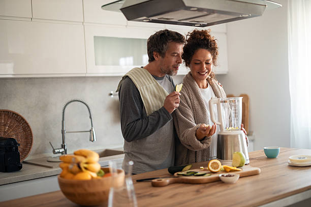 istock Happy Couple Preparing Fresh Juice in a Modern Kitchen With Blender and Fruit 2253469438