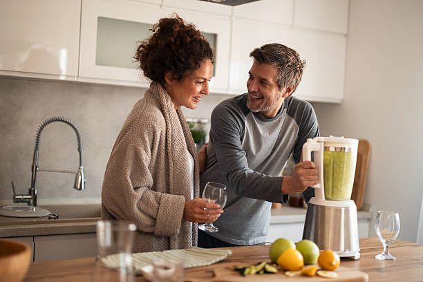istock Happy Couple In Modern Kitchen Blending Smoothie, Sharing Laughs, And Fresh Fruit With Blender 2253470043