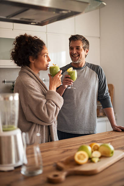 istock Casual Couple Enjoys Green Smoothies in Modern Kitchen, Sharing Laughs and Conversation 2253470198