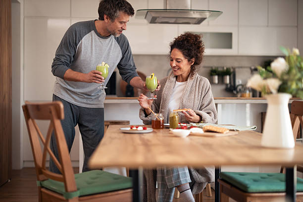 istock Couple Toasting With Green Smoothies At Kitchen Table During Cozy Brunch 2253470899