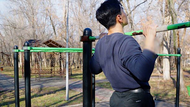 istock Man doing pull ups on bars in the outdoor sports park. 2253470916
