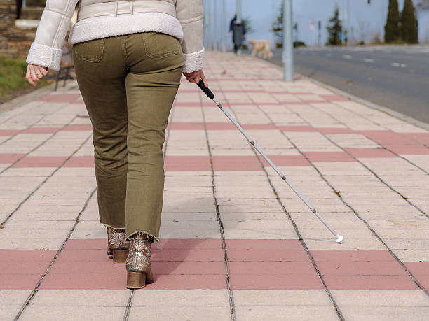 Woman walking sidewalk with white cane for independent navigation