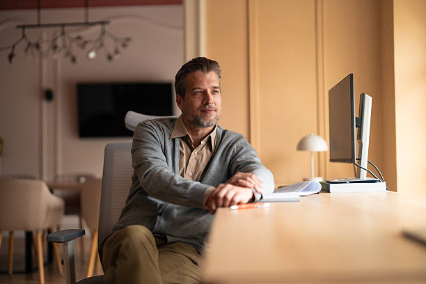 istock Businessman In Modern Office At Desk With Computer Monitors And Documents 2253474817