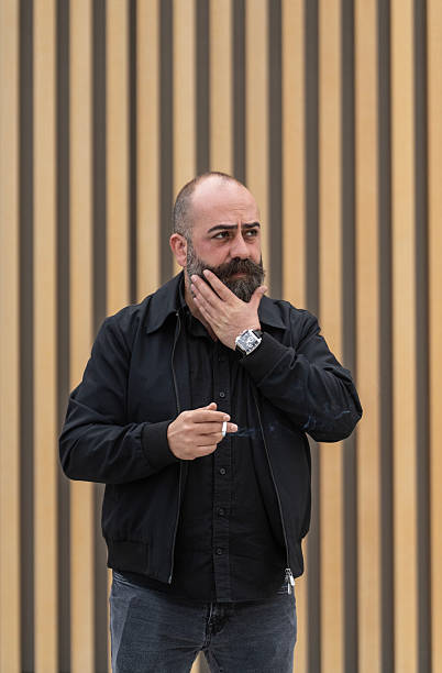 istock Bearded Man Smoking a Cigarette Outdoors 2253476322