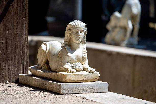 Pompei â Campania â Italy â 08-25-2025: A small stone sphinx sculpture rests on a low plinth in bright sunlight at the Ruins of Pompeii within an ancient outdoor courtyard.
