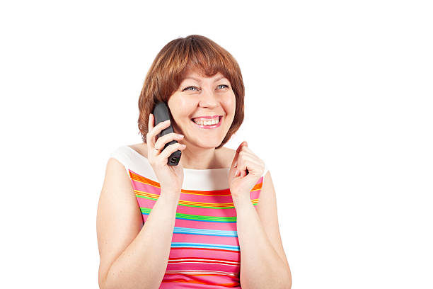 A young woman talks on a phone and smiles. The image is isolated on a white background.