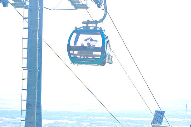 Cable car gondola with a man looking out, transporting passenger over a scenic landscape. Travel and adventure concept for mountain resort advertisements.
