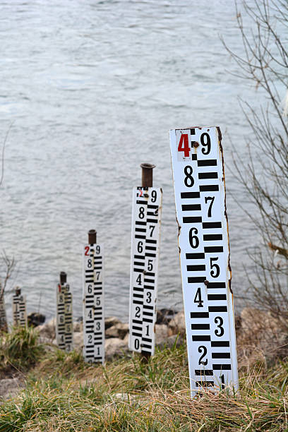 Water level at the dam, A water gauge stick in the middle of a river, showcasing accurate water level measurement with a scenic backdrop of mountains and cloudy sky