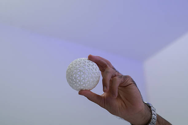 The focus is on the researchers' hands as they work with a 3D printer to print a clear white plastic model, using cutting-edge, spot-on technology in the lab.