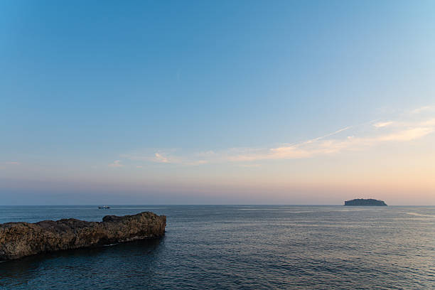 Crete, Greece coastal path along rugged cliffs at sunset. A serene Mediterranean landscape with rocky terrain, low vegetation, and a calm sea to the left. Perfect for travel, nature, hiking, and scenic imagery celebrating coastal beauty and peaceful sunset moments in Greece.