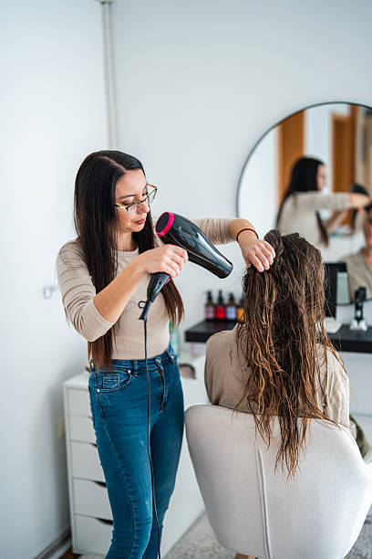 istock Young Caucasian Stylist Using Hairdryer in Spa Salon Setting 2253486448