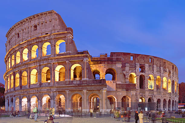 The Colosseum is illuminated at night in Rome, Lazio, Italy, showing the exterior arcades of the Flavian Amphitheatre. Built in the 1st century CE, it was the largest arena of Imperial Rome and remains a defining monument of Roman public architecture.