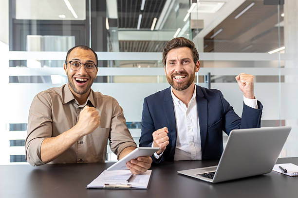 istock Two colleagues celebrating success at work with a tablet and a laptop 2253495998