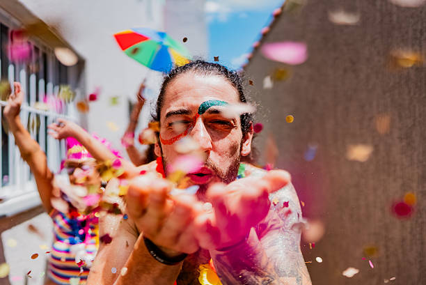 istock Portrait of a young man blowing confetti in Carnival Celebration 2253499430