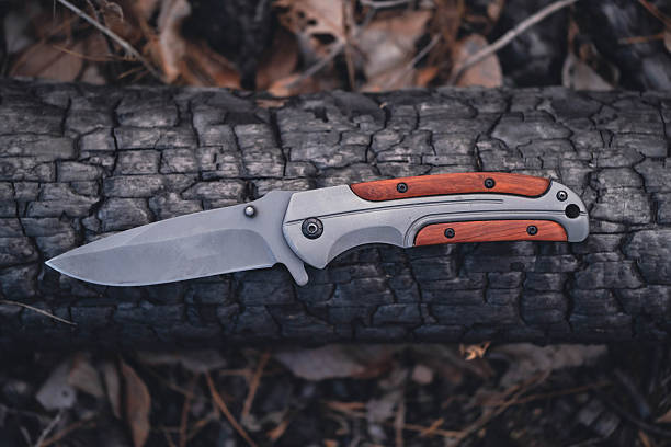 istock Hunting knife on background charred tree trunk. View from above. 2253499974