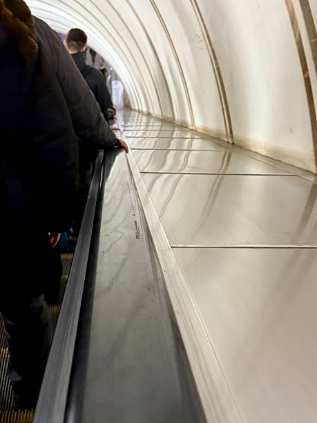 istock Commuter Descending Subway Escalator During Rush, Blurred Overhead Lights, Tiled Arched Tunnel, Long Perspective With Figures Queued Ahead 2253500119