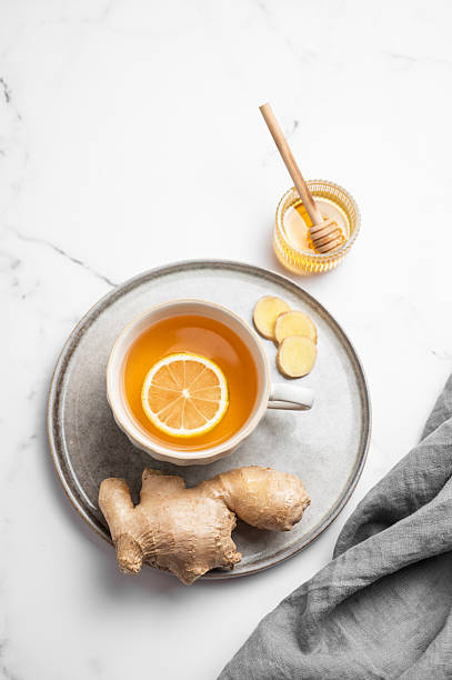 istock A cup of hot tea with fresh lemon and ginger on a plate on a light marble background 2253503396