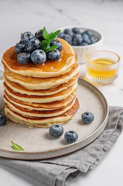Pancakes and fresh blueberries drizzled with sweet sauce on a plate on a marble background