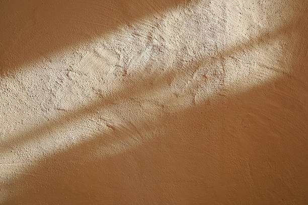 istock Light and shadow on a textured wall in a warm indoor space during the day 2253504421