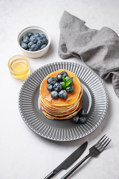 istock Stack of pancakes with fresh blueberries and suryp on a gray plate on a light background 2253504474