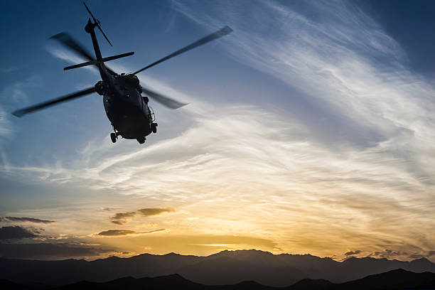 Military Helicopter flying against sunset sky