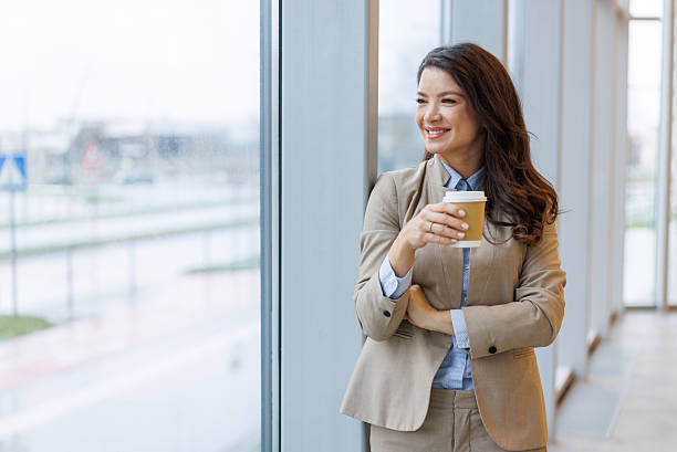 istock Businesswoman drinking coffee and looking out office window 2253513526