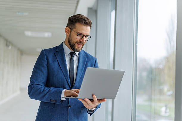 istock Businessman networking on laptop in modern office building 2253513614