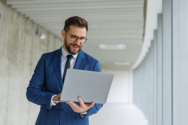 istock Professional businessman standing in hallway using laptop 2253513667