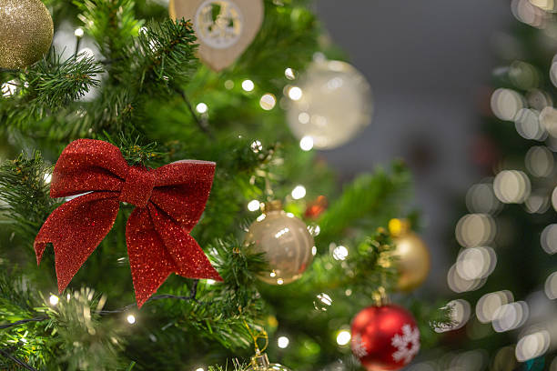 istock A decorated Christmas tree glows with warm white lights, featuring a red glitter bow and gold ornaments, creating a festive and elegant holiday atmosphere with soft bokeh in the background. 2253517258