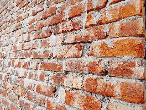 Close-up view of a weathered red brick wall with light gray mortar, featuring rough textures and natural color variation. Ideal background for construction, architecture, design, or urban-themed projects.