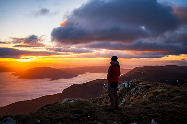 istock Hiker on Rocky Mountain Ridge Observing Sunset Above Cloud-Covered Valley 2253522016