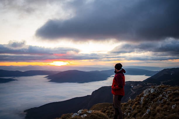 istock Close-Up of Hiker Standing on Mountain Ridge at Sunset Above Cloud Layer 2253522088