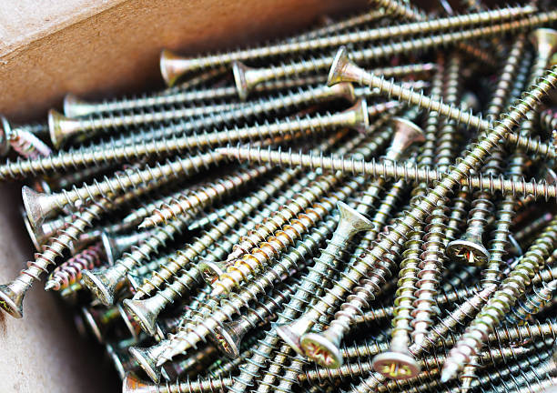 Screws background, close-up. Metal screws in box for construction projects, home repairs. Variety of metal screws are neatly organized in box, showcasing their shiny surfaces and spiral threads.