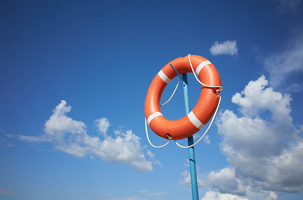 Red sunny lifebuoy on a pole cloudy blue sky background