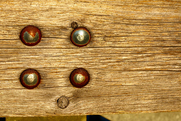 Weathered wood plank showing four rusty metal studs and rustic texture