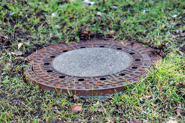 istock Rusty metal manhole cover in green grass 2253525611