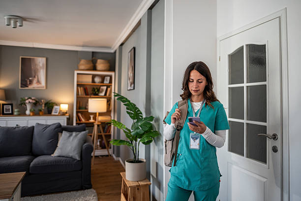istock Female nurse using smartphone arriving for house call 2253528201