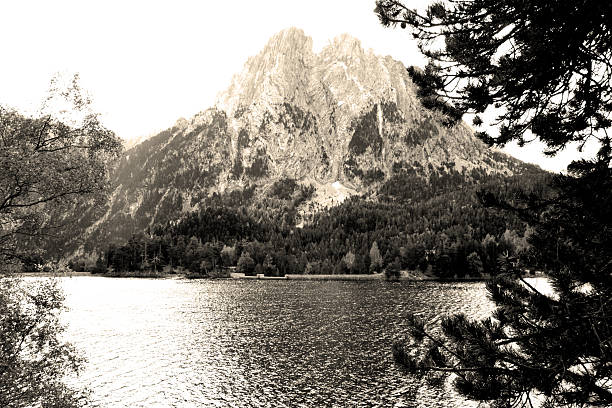 Sepia-toned landscape of a mountain and lake surrounded by trees.
