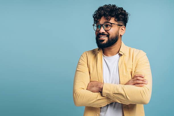 istock Confident middle eastern man with glasses smiling looking away with crossed arms on blue background 2253531134