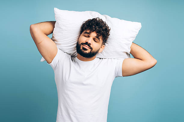 Handsome middle eastern man sleeping peaceful rest on pillow with closed eyes isolated on blue background. Relaxing concept